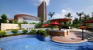 a large swimming pool with red umbrellas and a building at Fliport Hotel Zhangzhou Yuanshan in Zhangzhou