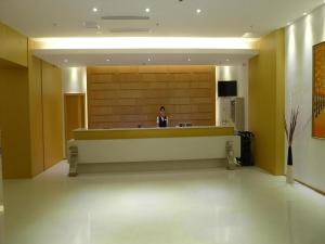 a woman sitting at a counter in a lobby at GreenTree Inn Shanghai Caohejing Development Zone Songjiang Park Jiuxin Road Business Hotel in Chunshen