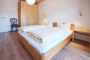 uma grande cama branca num quarto com piso em madeira em AlpenApart Montafon - Appartement Sennerei em Schruns