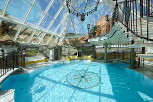 einem großen Pool in einem Gebäude mit Glasdecke in der Unterkunft VILA VITA Burghotel Dinklage in Dinklage