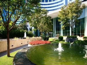 a pond in front of a building with a fountain at Jianguo Garden Hotel in Beijing