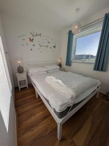 a bedroom with a bed and a window at The Green One, Sunbeach, Scratby - Two bed chalet, sleeps 5, free Wi-Fi, pet friendly, bed linen and towels included plus free entry to onsite clubhouse in Scratby
