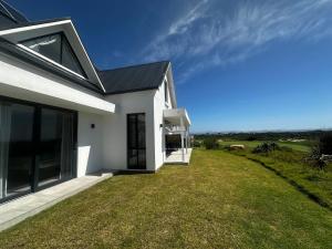 a white house with a grassy yard in front of it at Seabreeze Golf Retreat in St Francis Bay