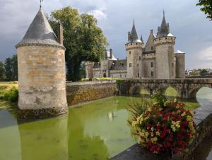 a castle with a bridge over a body of water at Maison de marinier les pieds dans l'eau face à la Loire in Sully-sur-Loire