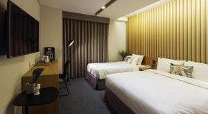 a hotel room with two beds and a desk at Hotel Denim Seoul in Seoul