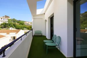 a balcony with green chairs and a view at Dúplex Sa Tarongeta - 5' playa I vistas I terraza 20m2 I ascensor I equipado in Cadaqués