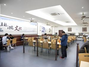 un grupo de personas sentadas en mesas en un restaurante en GreenTree Inn Shanghai Minhang Development Zone Subway Station Business Hotel, en Shanghái