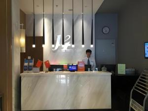 邯鄲市にあるJinjiang Inn Handan Zhonghua Nan Street Xueyuan Bei Roadの店のカウンターに座る男