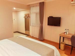 a hotel room with a bed and a television at GreenTree Inn Kunshan Shimao Plaza Business Hotel in Penglang