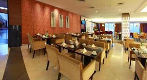 a dining room with tables and chairs in a restaurant at Grand Basko Hotel in Minangkabau International Airport