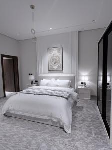 a white bedroom with a large bed and two tables at منتجع دارك in Hail