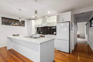 Una cocina con gabinetes blancos y un refrigerador blanco. en Idyllic Aireys Retreat - where ocean & hills meet, en Aireys Inlet 13 fotos más