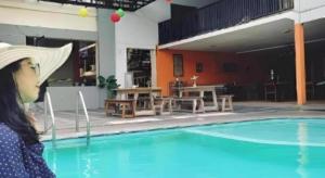 a woman wearing a hat standing next to a swimming pool at Hotel Intan Cirebon in Cirebon