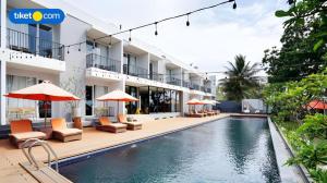 un hôtel avec une piscine dotée de chaises et de parasols dans l'établissement Double G Resort Anyer, à Babagan