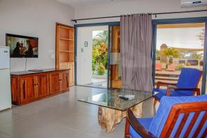 a living room with a glass table and blue chairs at Résidence Sarimanok in Nosy Be