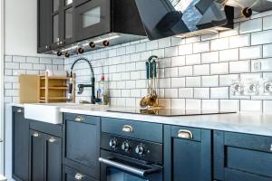 a kitchen with blue cabinets and a white tiled wall at Bright Apartment Near the lake in Bordeaux