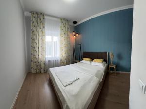 Un dormitorio con una cama con sábanas blancas y cortinas amarillas. en Уютная и комфортная 3х комнатная в новом центре, en Uralsk