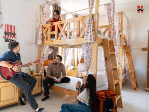 un groupe de personnes assises dans une pièce avec un lit superposé dans l'établissement Moustache Hostel Bir, à Bir