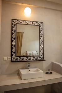 a bathroom with a sink and a mirror at Résidence Sarimanok in Nosy Be