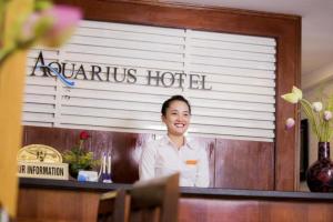 a woman standing behind a counter in a restaurant at Aquarius Hotel in Hanoi