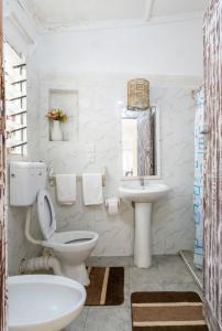 a white bathroom with a toilet and a sink at Paradise Lagoon B&B in Watamu +69 photos