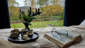 a table with a vase of flowers and a book and glasses at Domek z widokiem Wilczy Jar in Jarnołtówek