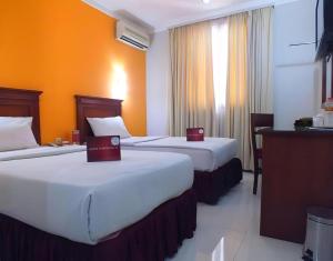 two beds in a hotel room with orange walls at Sofyan Inn Tebet Family Friendly in Jakarta +158 photos
