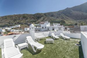 un grupo de sillas blancas sentadas en un techo en Gar House, en Caleta de Interián