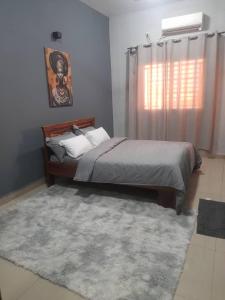 - une chambre avec un lit, un tapis et une fenêtre dans l'établissement Appartement Moderne PanneaUx Solaires Golf, Bamako, à Bamako 2 autres photos