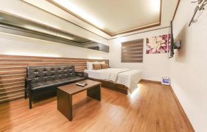 a bedroom with a bed and a couch and a table at H Hotel in Ulsan
