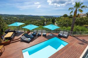 a swimming pool on a wooden deck with blue umbrellas at Suite Île du Levant - Jardin & Piscine - 4 pers in La Croix-Valmer