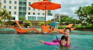two children are swimming in a swimming pool at PARK HOTEL Cawang Jakarta in Jakarta