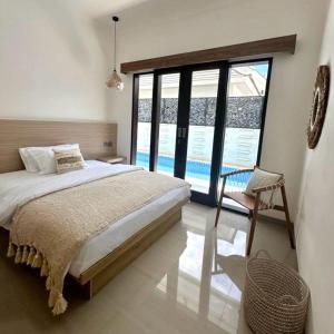 a bedroom with a large bed and large windows at Villa Kelle - Uluwatu Nusa Dua in Nusa Dua