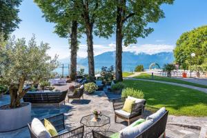 a patio with couches and tables with mountains in the background at Hotel du Léman - Jongny in Vevey