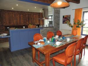 una cocina con mesa de madera y sillas naranjas en Beluga, en La Godivelle
