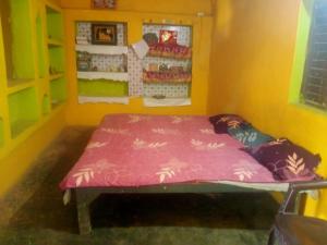 a small room with a bed in a yellow room at Ramanuj Rural Homesty in Raipura