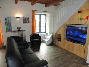 sala de estar con sofá y TV de pantalla plana en Beluga, en La Godivelle