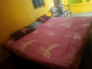 a bed with a pink bedspread with leaves on it at Ramanuj Rural Homesty in Raipura