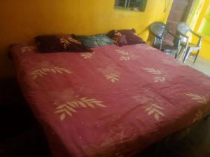 a bed with a red blanket with leaves on it at Ramanuj Rural Homesty in Raipura