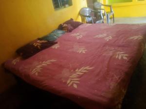 a bed with a pink blanket with flowers on it at Ramanuj Rural Homesty in Raipura
