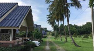 une maison avec une voiture garée à côté d'un palmier dans l'établissement OYO 75380 Bannoichynum Resort Kanchanaburi, à Ban Tha Kilen (1)