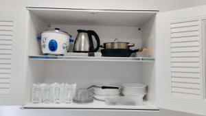 a white pantry with dishes and a tea pot at Keerana Villa in Uttaradit
