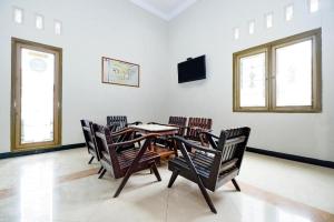 a dining room with a table and chairs and windows at Super OYO 2436 Hotel Kencana in Tegal