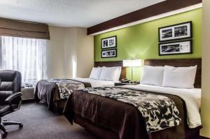 a hotel room with two beds and a chair at Sleep Inn Airport - Billy Graham Parkway in Charlotte