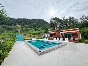 een zwembad met witte stoelen en een huis bij Forest Hill Lanta in Koh Lanta