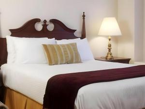 a bedroom with a large bed with white sheets and a lamp at Hilgard House Westwood Village in Los Angeles