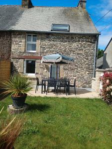 Una mesa y sillas con una sombrilla en un patio. en Gîte l'orée de la forêt légendaire, en Néant-sur-Yvel