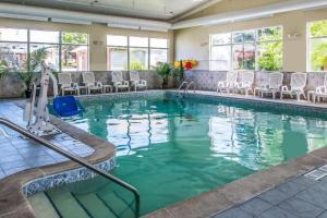a swimming pool in a hotel with chairs and tables at Quality Inn & Suites Ann Arbor Hwy 23 in Ann Arbor
