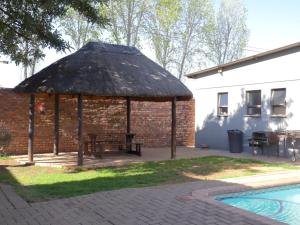 a pavilion with a picnic table and a brick building at Andela Guesthouse in Bloemfontein