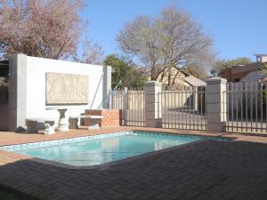 a swimming pool in a yard with a fence at Andela Guesthouse in Bloemfontein